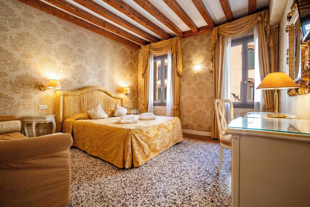 A hotel room with a bed, a chair, a desk, and a mirror.