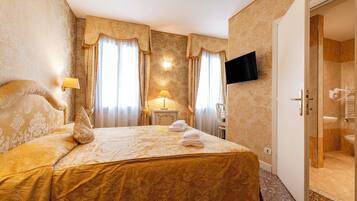 Une chambre d’hôtel avec un grand lit, deux lampes de chevet, un téléviseur à écran plat et une salle de bain visible à travers une porte ouverte.