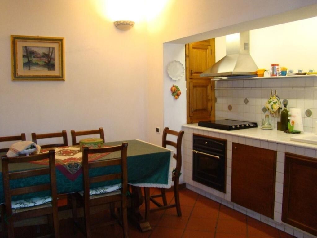 A compact kitchen with wooden cabinets, a stove, and a dining area with a table and chairs.