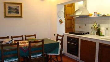 A compact kitchen with wooden cabinets, a stove, and a dining area with a table and chairs.