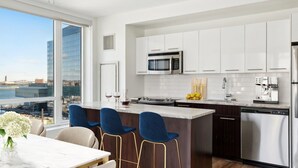 A modern kitchen with white cabinets, stainless steel appliances, and a view of the city. - Marvelous 2-bedroom apartment in Boston with WiFi (Boston)