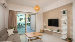 A modern living room with a sofa, a coffee table, a TV mounted on a wall, and a view of the outdoors.