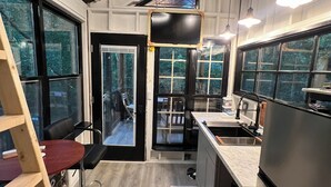 Une cuisine moderne dotée d’un grand îlot central, d’appareils électroménagers intégrés et de grandes fenêtres offrant une vue sur l’extérieur.