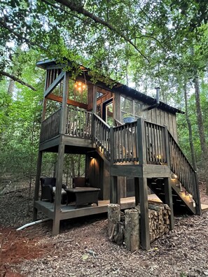 A wooden cabin with a balcony, a fireplace, and a dining area. - Holly Trail Treehouse in Anderson w/WIFI, AC, Smart TV, Full Bath and washer (Anderson)