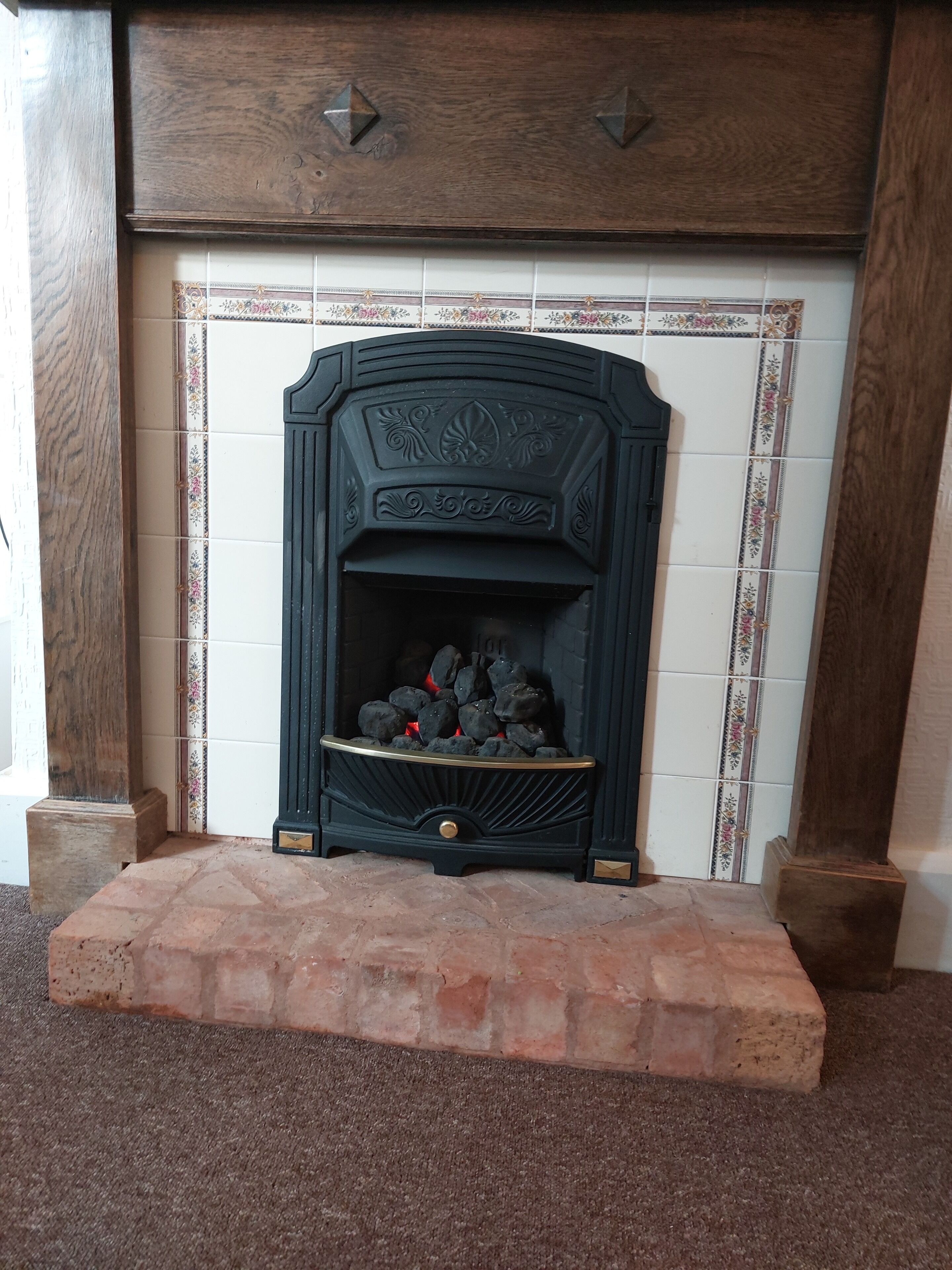 Une cheminée ornée de carreaux décoratifs et encadrée de briques.