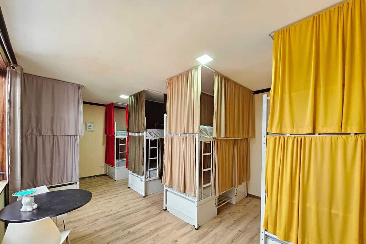 A dormitory room with bunk beds, a small table, and a chair.
