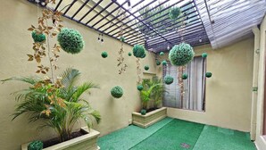 Zona exterior coberta amb gespa artificial, plantes en testos i vegetació penjant.