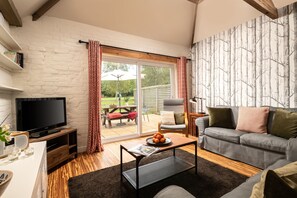A living room with a television, sofa, coffee table, and a sliding glass door leading to an outdoor area.
