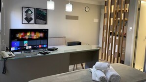 A hotel room with a glass desk, a bed with towels, a clock, and artwork on the wall. - Get a Flat 805 Região Jardins SP (São Paulo)