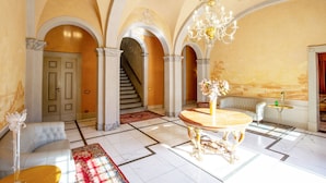 A grand lobby with a marble floor, a round table, a sofa, and a staircase. - Eighteenth-century Tuscan Villa Tricolle (Fucecchio)