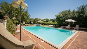 A rectangular swimming pool with a tiled deck, surrounded by lounge chairs and umbrellas. - Eighteenth-century Tuscan Villa Tricolle (Fucecchio)