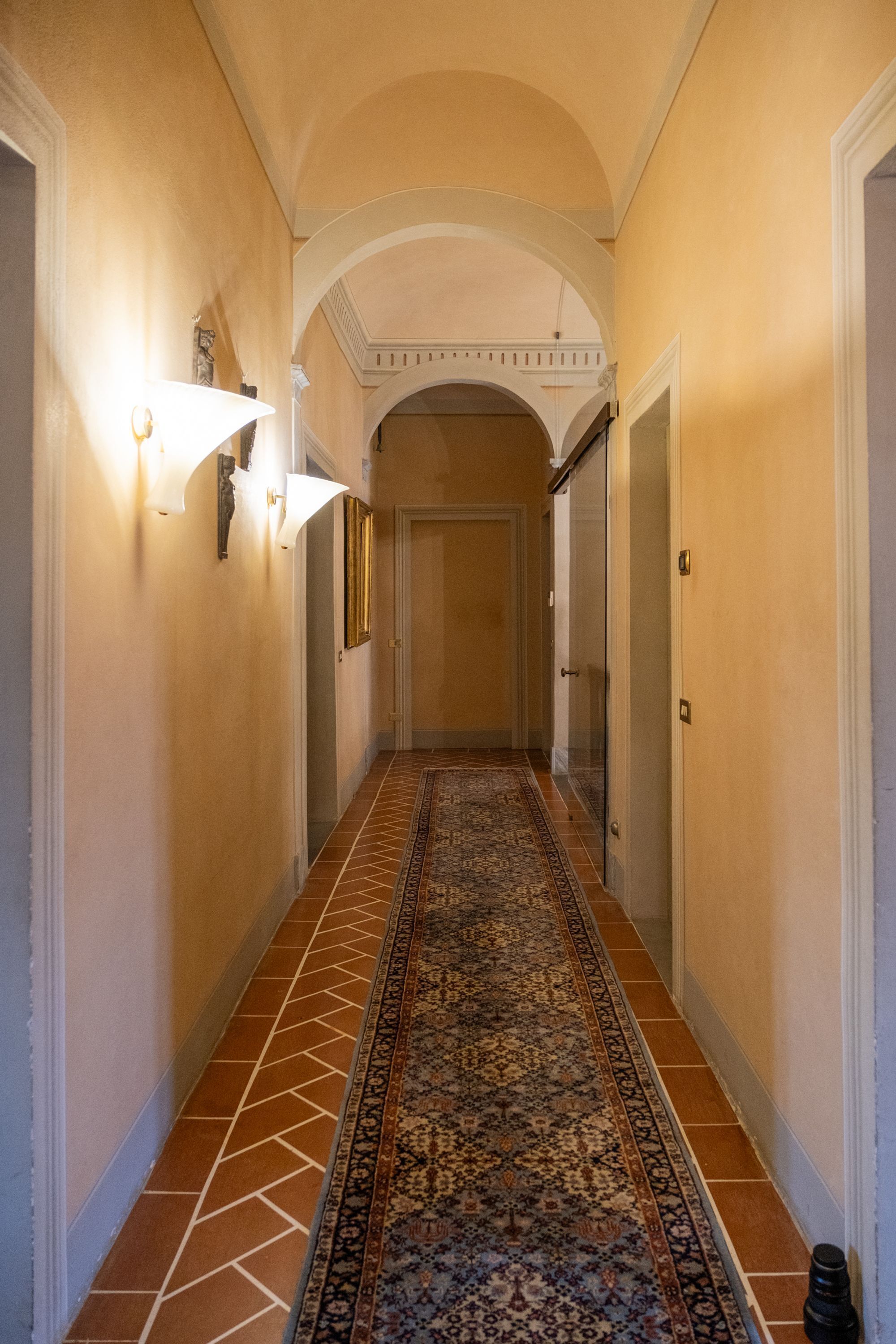 Ein Flur mit Teppichmuster, weißen Wänden und einer verzierten Decke.
