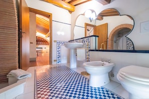 A bathroom with a checkered floor, a sink, a bidet, and a toilet.