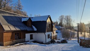 A wooden cabin with a sloped roof, surrounded by snow-covered ground and trees. - Vysoke nad Jizerou Kds007 (Vysoké nad Jizerou)