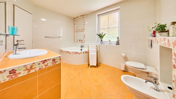 Ein Badezimmer mit Waschbecken, Badewanne, Toilette und einem Fenster mit Jalousien.