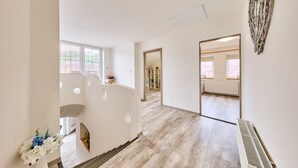 Ein geräumiger Hotelkorridor mit Holzboden, weißen Wänden und großen Fenstern.