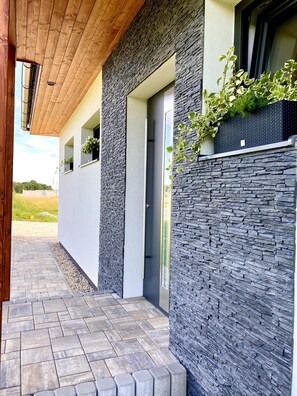 A modern building with a stone facade, a wooden ceiling, and a paved walkway. - Doksy Ldma001 in Doksy (Doksy)