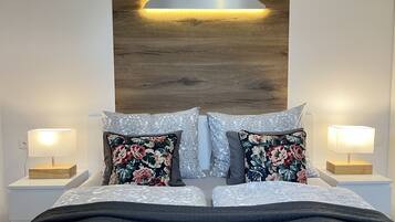A neatly made bed with floral pillows, a wooden headboard, and bedside lamps.