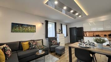 A modern living room with a sofa, a dining table, and a kitchen area with cabinets and appliances.