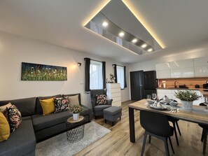 A modern living room with a sofa, a dining table, and a kitchen area with cabinets and appliances. - Doksy Ldmb002 in Doksy (Doksy)