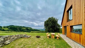 Ein modernes Holzgebäude mit einer Steinwand und einer Rasenfläche mit Picknicktischen.