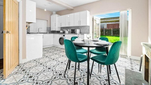 Una cocina moderna con armarios blancos, una lavadora y un comedor con mesa y sillas.