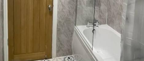 A bathroom with a shower enclosure, a bathtub, and a patterned floor.