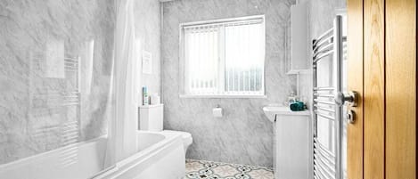 A bathroom with a bathtub, toilet, and sink.