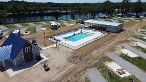 An aerial view of a campground with a swimming pool, RV parking, and a lake in the background. - Lake View Cabin, 2 Bedrooms, 13 miles from Jacksonville! (Maysville)