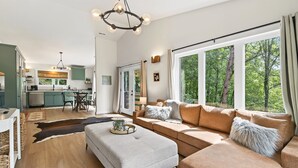 Un salon moderne comprenant un canapé, un pouf et un coin repas avec une table et des chaises.