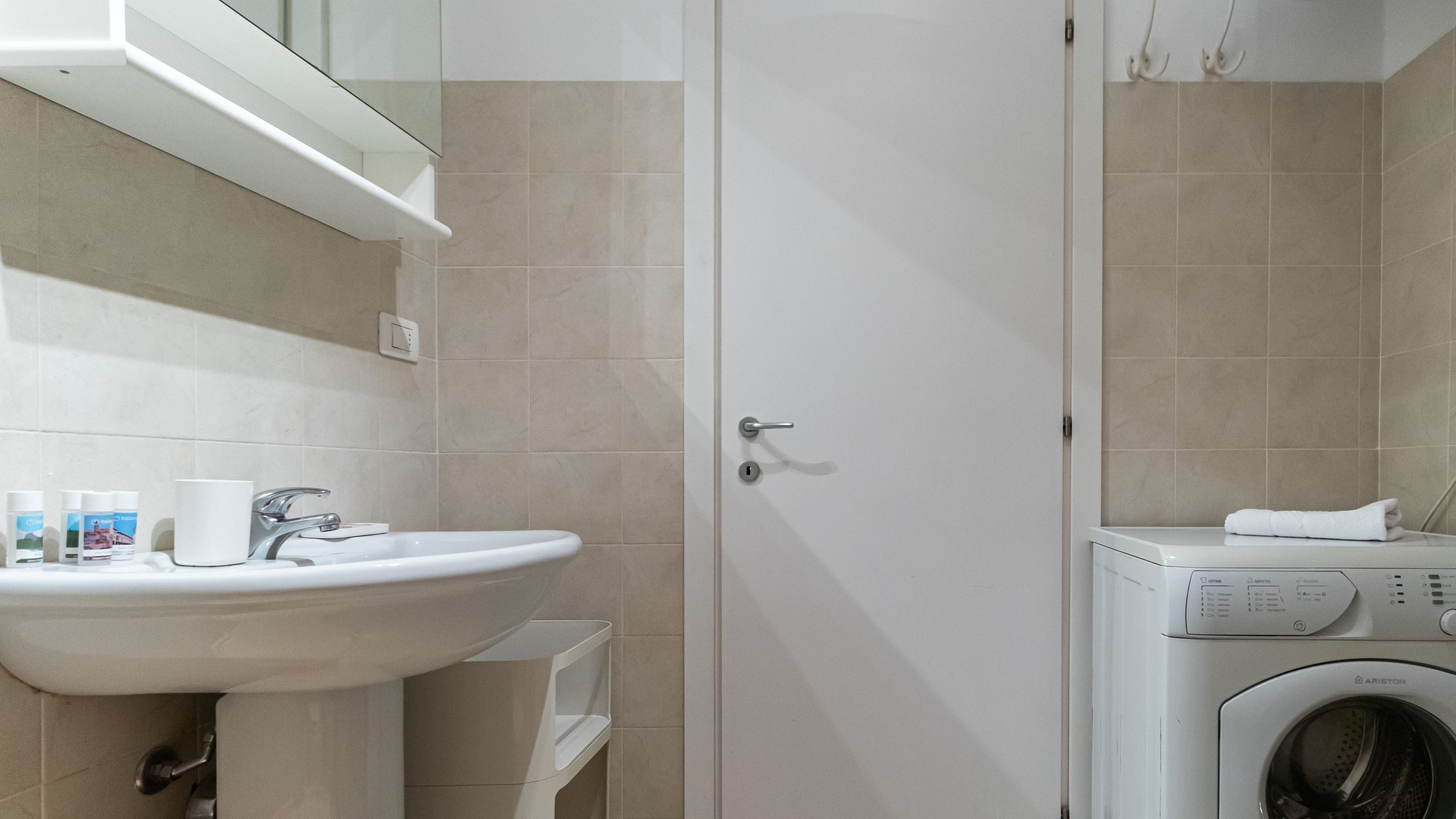 A bathroom with a sink, mirror, and a washing machine.