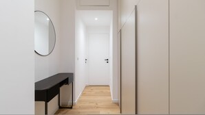 A narrow hallway with a wooden floor, a black countertop, and a round mirror on the left. - Italianway Comfort - D Aragona 2 (Milan)