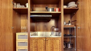 Eine kleine Küche mit Holzschränken, einer Edelstahl-Spüle und einem Metallregal.