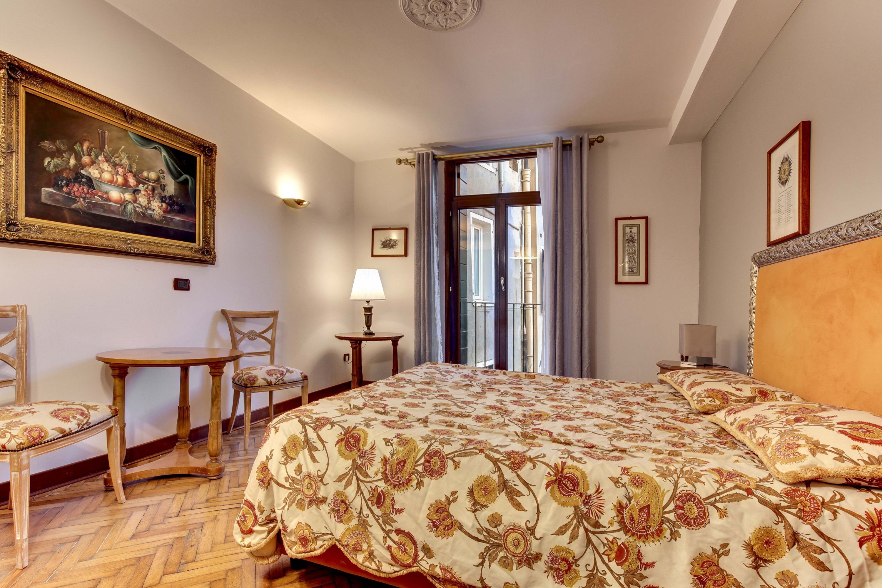 Une chambre d’hôtel avec un grand lit, une table à manger avec des chaises, une petite table avec une lampe et un tableau au mur.