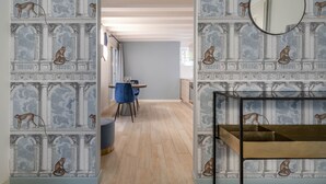 Une pièce au design moderne, avec un plancher en bois, une chaise bleue et un miroir rond accroché au mur.