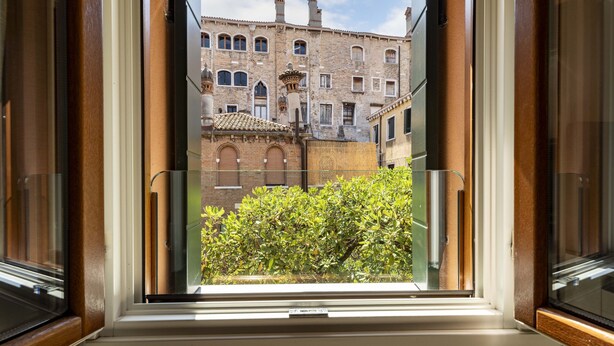 Una ventana que muestra un edificio con varias ventanas y un balcón.
