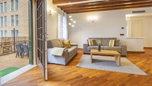 A spacious living room with a wooden floor, two grey sofas with cushions, a wooden coffee table, and a large window. - Tolentini Terrace - Locz (Venice)