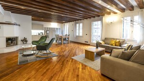 A spacious living area with wooden flooring, a green armchair, a sofa, and a dining table. - Tolentini Terrace - Locz (Venice)