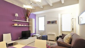 Un salon moderne comprenant un téléviseur, un canapé et un coin repas avec une table et des chaises.
