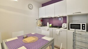 Une cuisine de taille réduite avec des meubles blancs, un four à micro-ondes et une cuisinière.