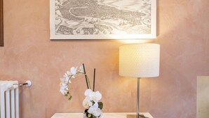 A white table with a white orchid vase, a lamp, and a framed map on the wall. - Doge Palace 8 - Locz (Venice)