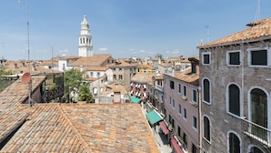 A historic town with traditional buildings, a prominent bell tower, and a clear sky. - Doge Palace 8 - Locz (Venice)