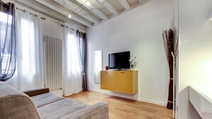 Una sala de estar moderna con un sofá, un televisor sobre un mueble blanco y un radiador.