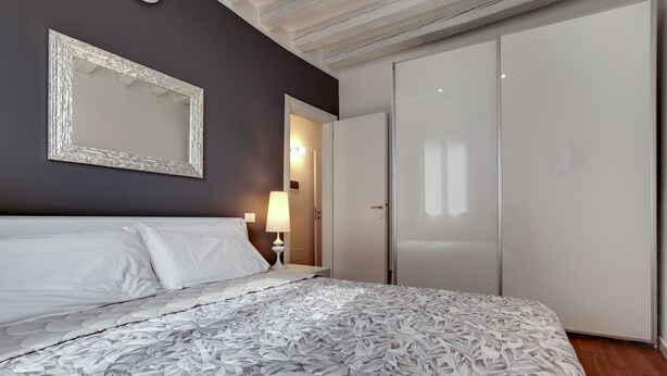 Un dormitorio con una cama grande, un armario y un espejo en la pared.