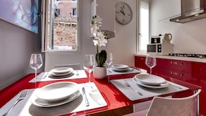 Una cocina moderna con encimeras rojas, armarios blancos y un reloj a la vista en la pared.