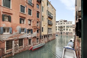 Un canal étroit, bordé de bateaux et d’immeubles historiques, avec un bâtiment plus imposant visible au loin.