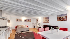 A modern, well-lit room with a bed, a dining table, and a kitchen area. - Marco Polo Apartment by Wonderful Italy (Venice)