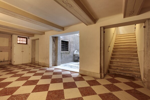 A hallway with a checkered floor, a staircase, and a door leading to a room. - Rialto Canal View by Wonderful Italy (Venice)