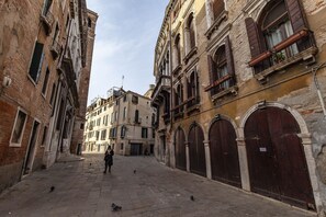 A narrow street with historic buildings, a person walking, and pigeons on the ground. - Residenza Valier by Wonderful Italy (Venice)