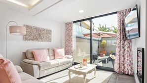 Una sala de estar moderna con sofá, mesa de centro y un amplio ventanal corredero que da a un patio exterior.